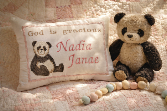 Music box pillow with embroidered panda and text, accompanied by a plush panda toy on a textured fabric background.