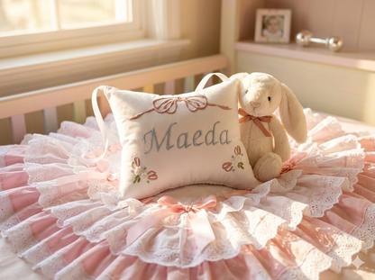 Crib with pink bedding, plush toy, and personalized music box pillow in a softly lit room.
