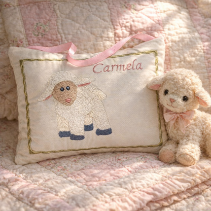 Decorative music box pillow with embroidered sheep design and a plush toy sheep on a quilted surface.