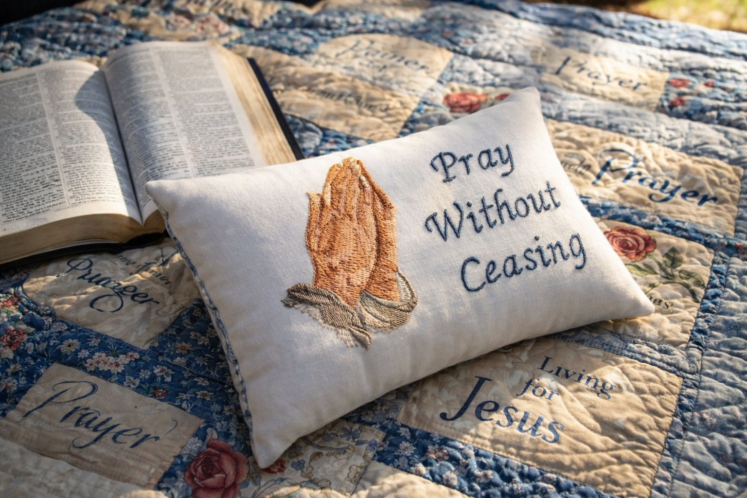 Decorative music box pillow with 'Pray Without Ceasing' text on a quilted surface with an open book.