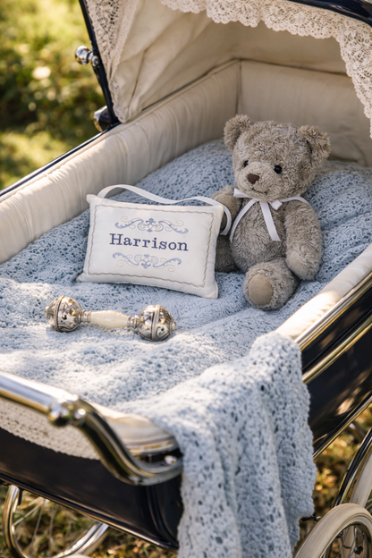 Baby carriage with teddy bear, music box pillow, and rattle on a blurred natural background