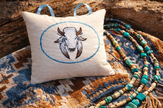 Decorative music box pillow with embroidered bison design on a textured surface with beads.