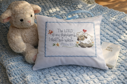 Stuffed lamb toy next to a decorative music box pillow with a sheep design and text on a blue textured surface.