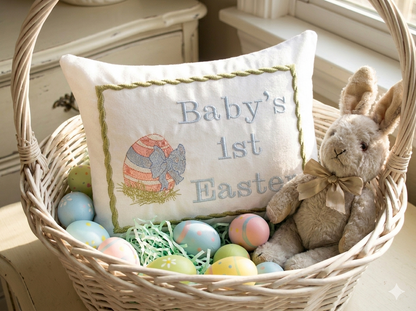 Wicker basket with 'Baby's 1st Easter' music box pillow, stuffed bunny, and colorful eggs.