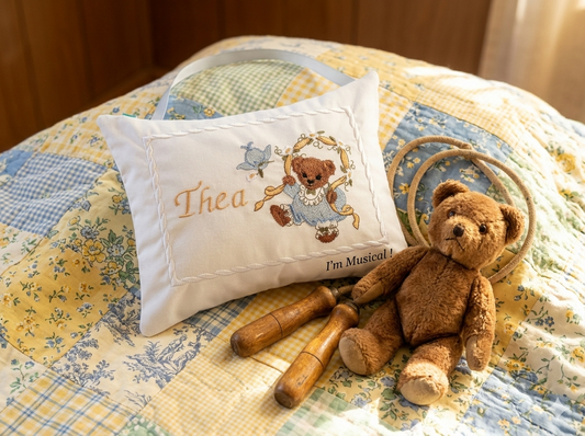 Teddy bear and decorative music box pillow on a quilted surface