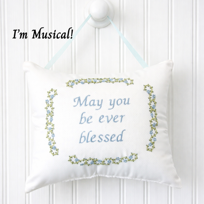 Decorative music box pillow with embroidered text and floral border on a white background