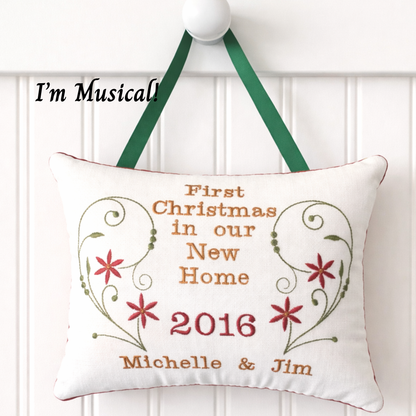 Decorative music box pillow with text 'First Christmas in our New Home 2016 Michelle & Jim' on a white background.