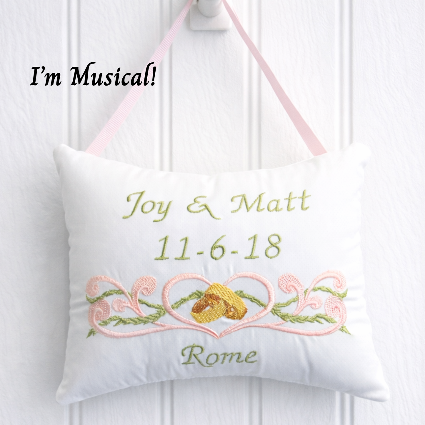 Decorative music box pillow with embroidered text and design on a white background