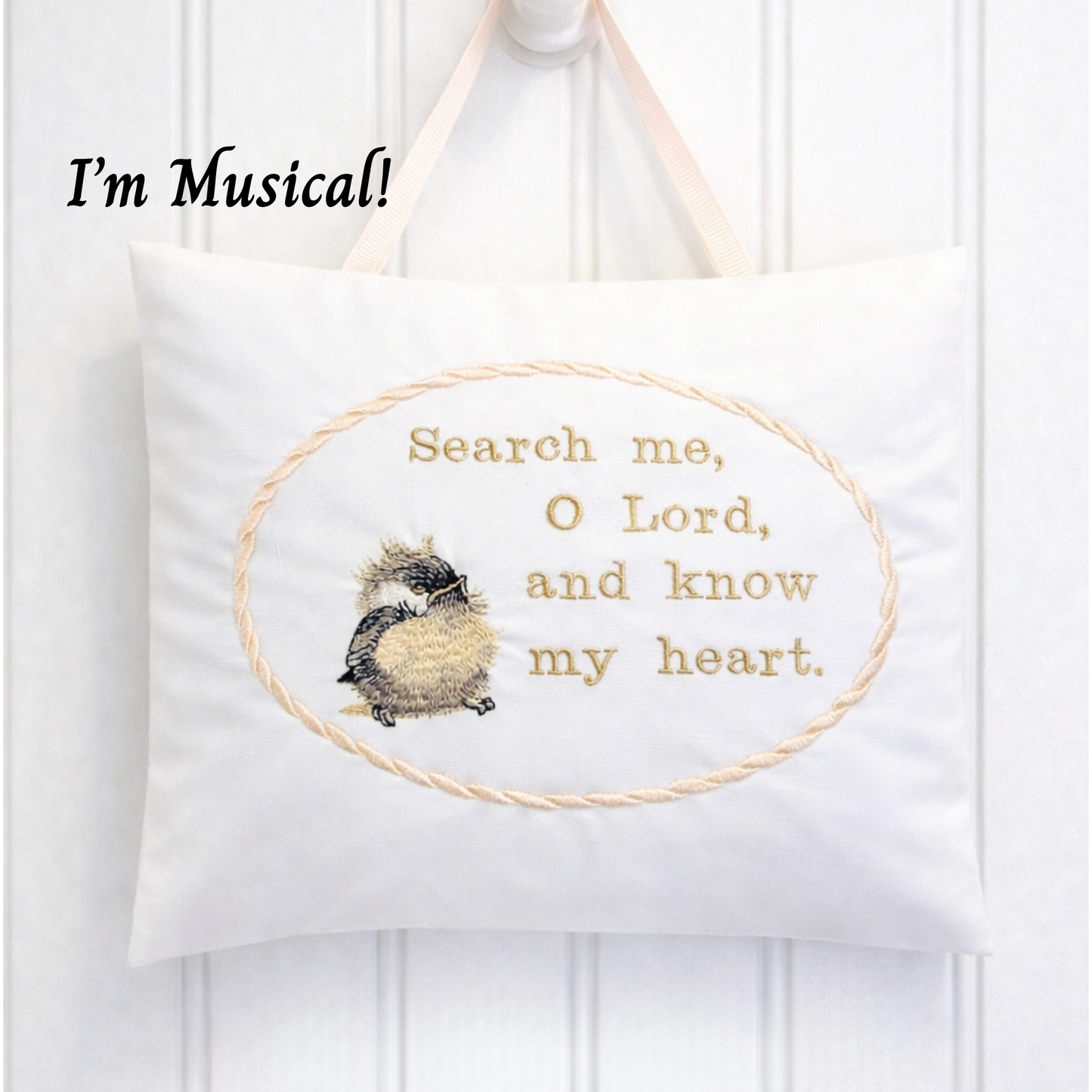 White music box pillow with embroidered design and text on a white background