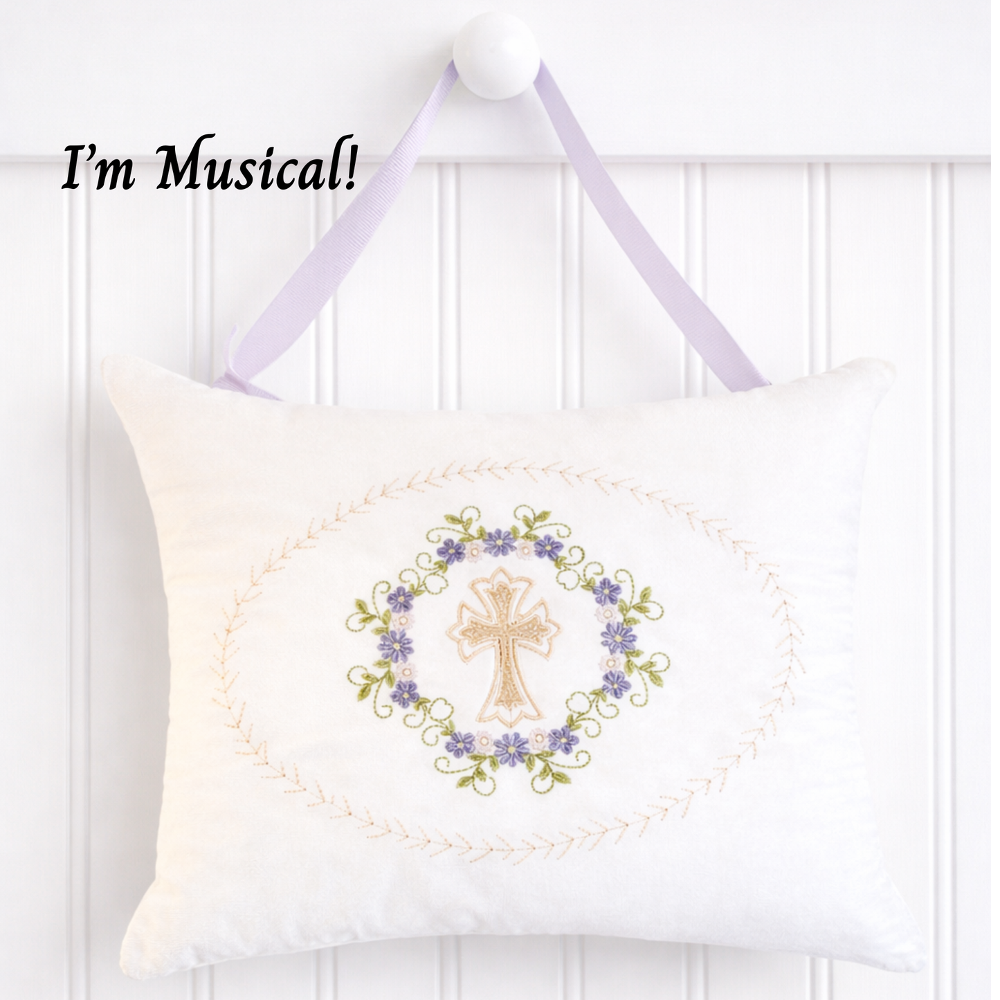 Decorative music box pillow with embroidered cross and floral design on a white background