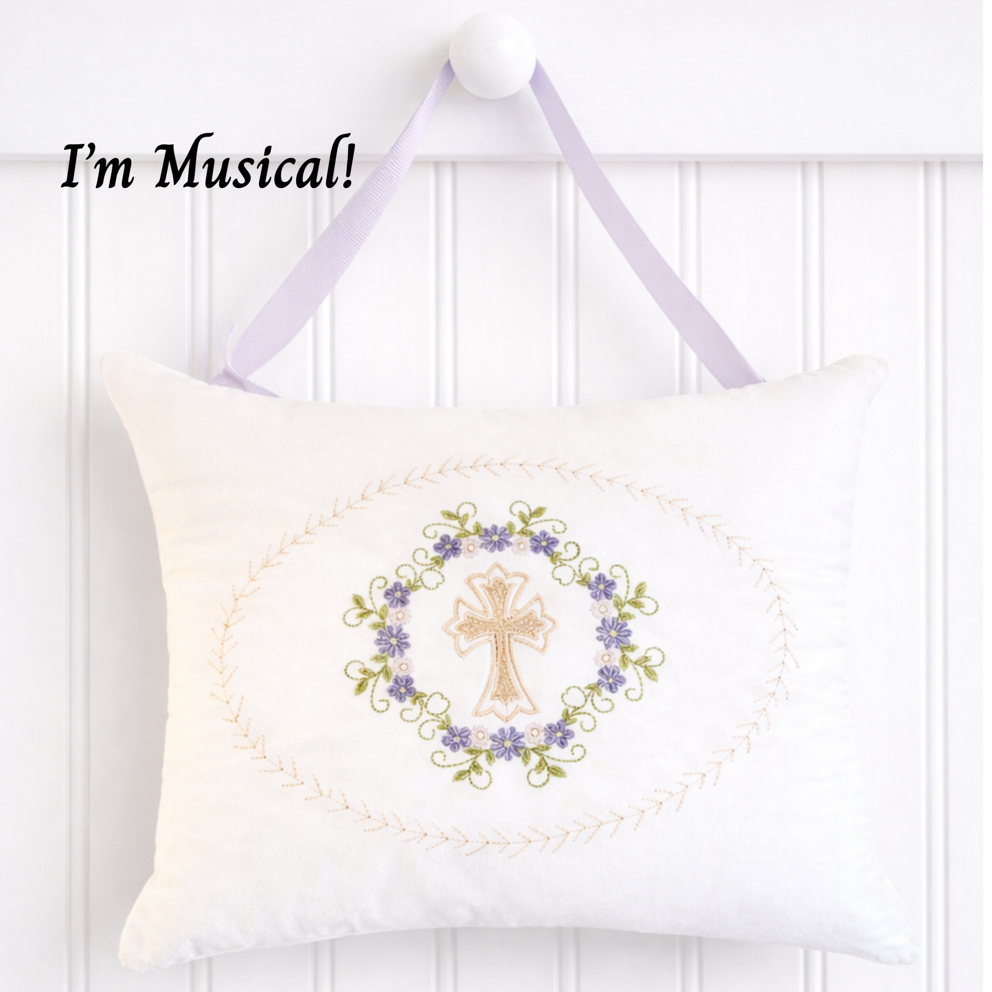Decorative music box pillow with embroidered cross and floral design on a white background