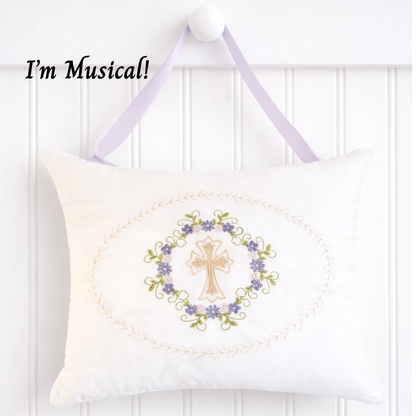 Decorative music box pillow with embroidered cross and floral design on a white background