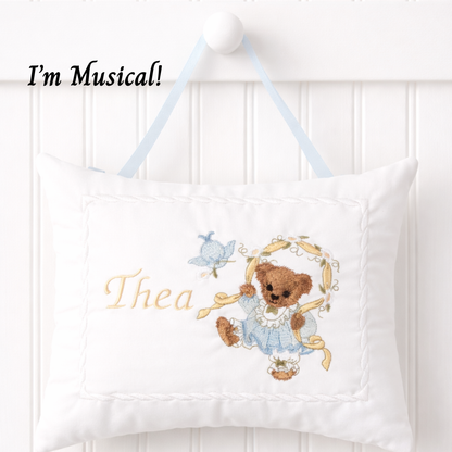 Decorative music box pillow with embroidered teddy bear and text 'I'm Musical! Thea' on a white background.