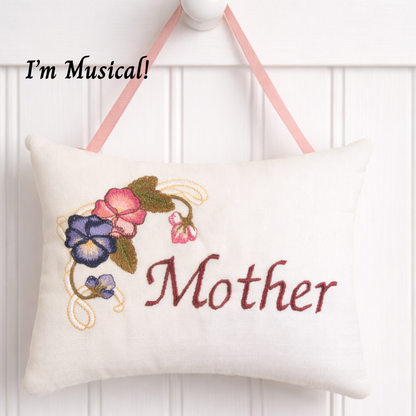Decorative music box pillow with embroidered floral design and 'Mother' text on a white background