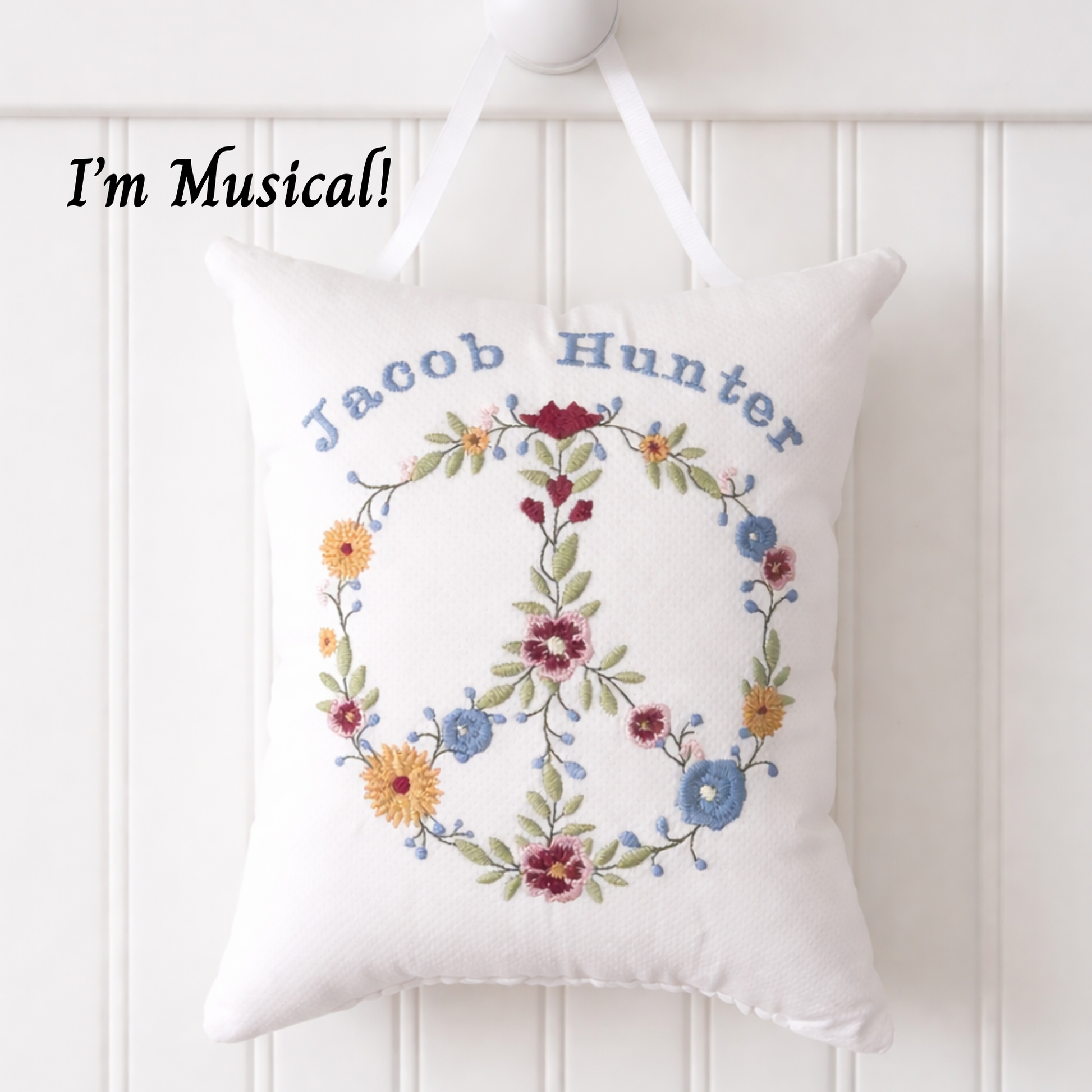 Decorative  music box pillow with floral design and embroidered name on a white background