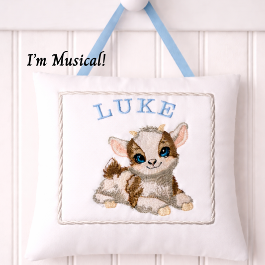 Music box pillow with a baby goat design and the name 'Luke' on a white background.