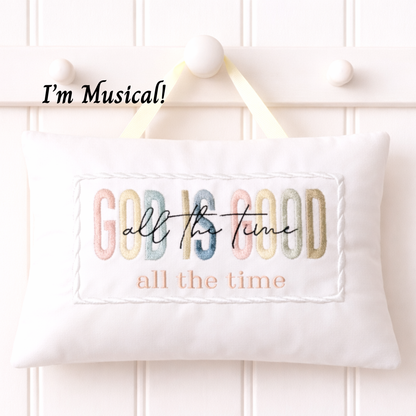 Embroidered music box pillow with colorful text 'GOD IS GOOD all the time' on a white background.