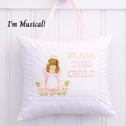 Decorative music box pillow with angel design and text 'Bless This Child' on a white background