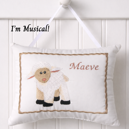 Decorative music box pillow with a sheep design and text 'I'm Musical! Maeve' on a white background