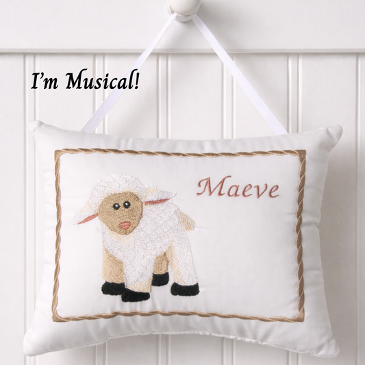 Decorative music box pillow with a sheep design and text 'I'm Musical! Maeve' on a white background