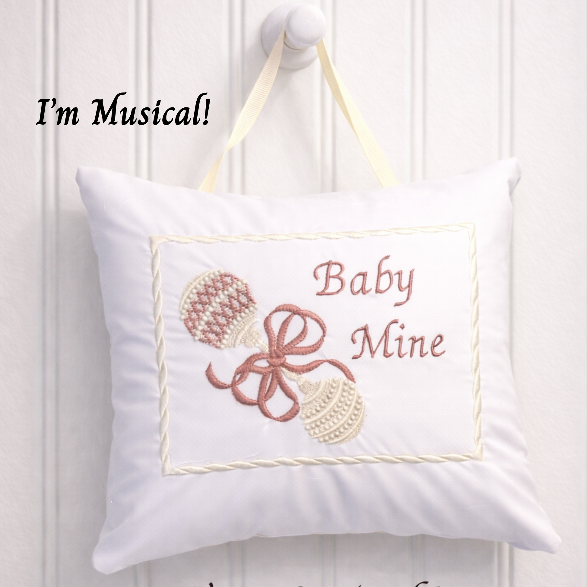 Decorative music box pillow with 'Baby Mine' text and musical notes on a white background