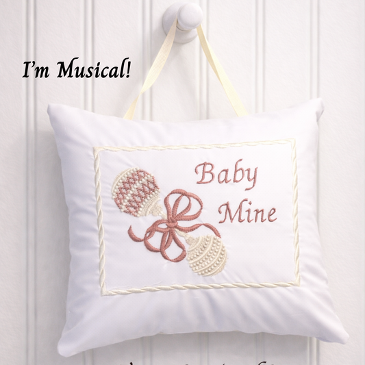 Decorative music box pillow with 'Baby Mine' text and musical notes on a white background