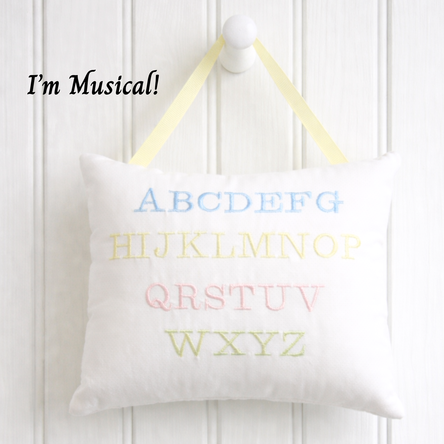 White music box pillow with colorful letters on a white background