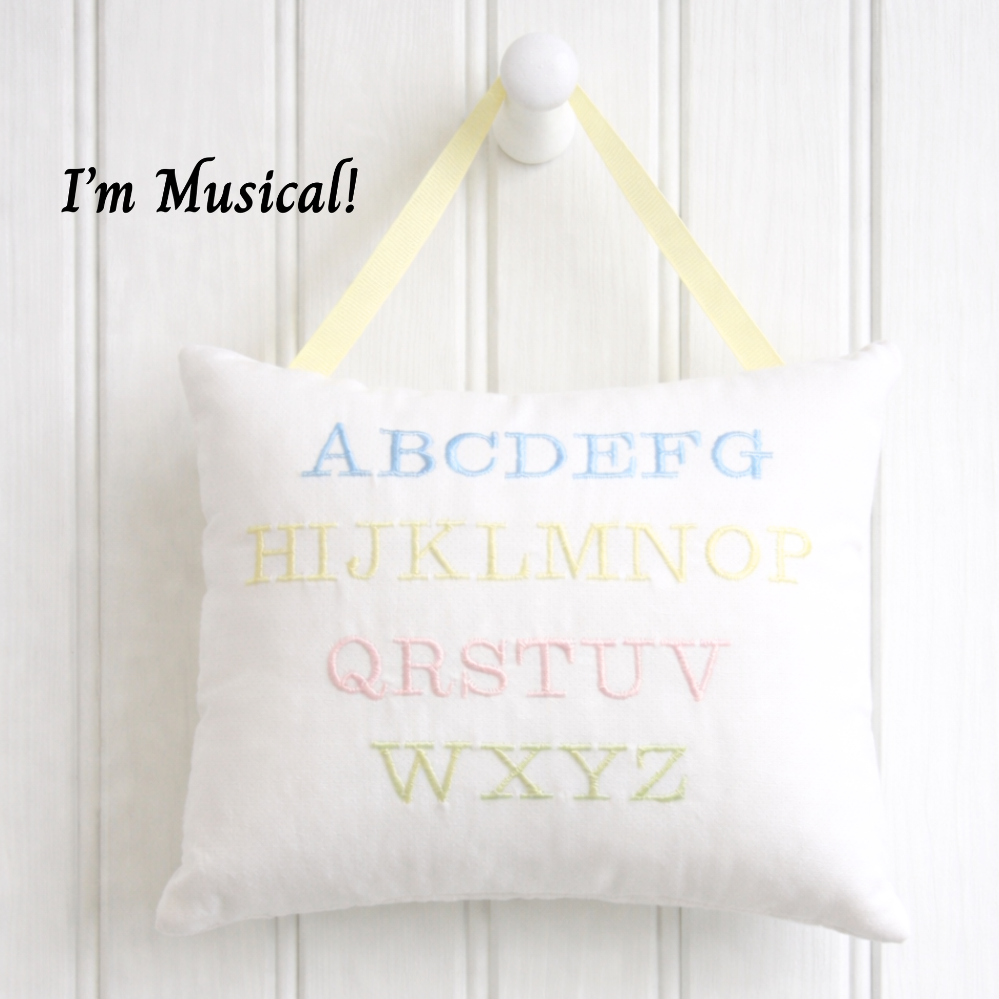 White music box pillow with colorful letters on a white background