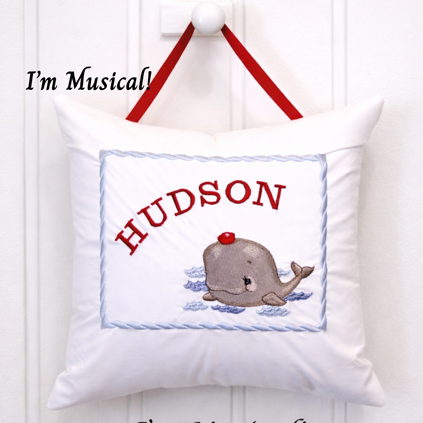 Decorative music box pillow with a whale design and the name 'Hudson' on a white background.