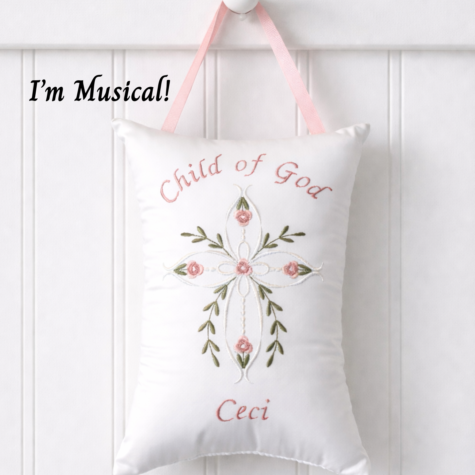 Decorative music box pillow with embroidered cross and floral design and text on a white background