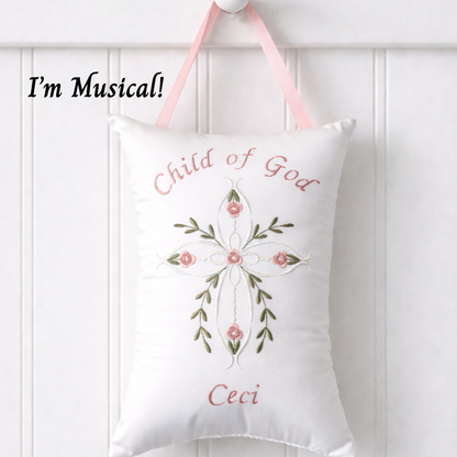 Decorative music box pillow with embroidered cross and floral design and text on a white background