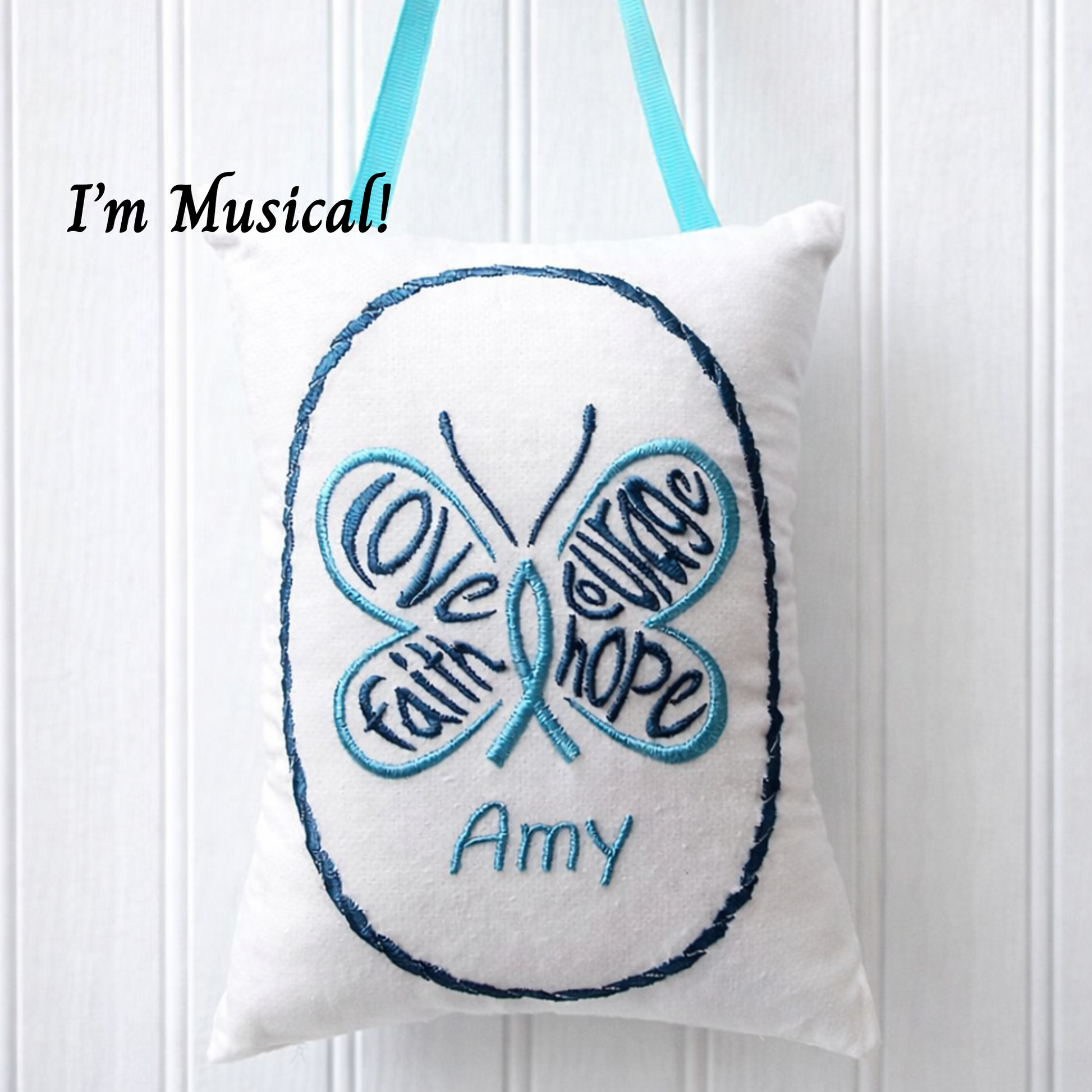 Butterfly-shaped music box pillow with embroidered text and 'I'm Musical!' text on a white background
