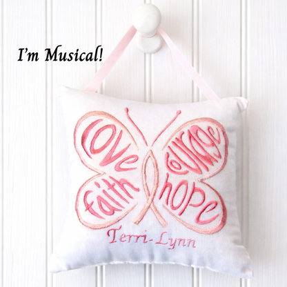 Butterfly-shaped music box pillow with embroidered text on a white background