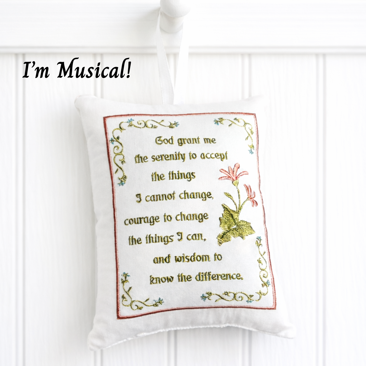 Decorative music box pillow with embroidered text and design on a white background