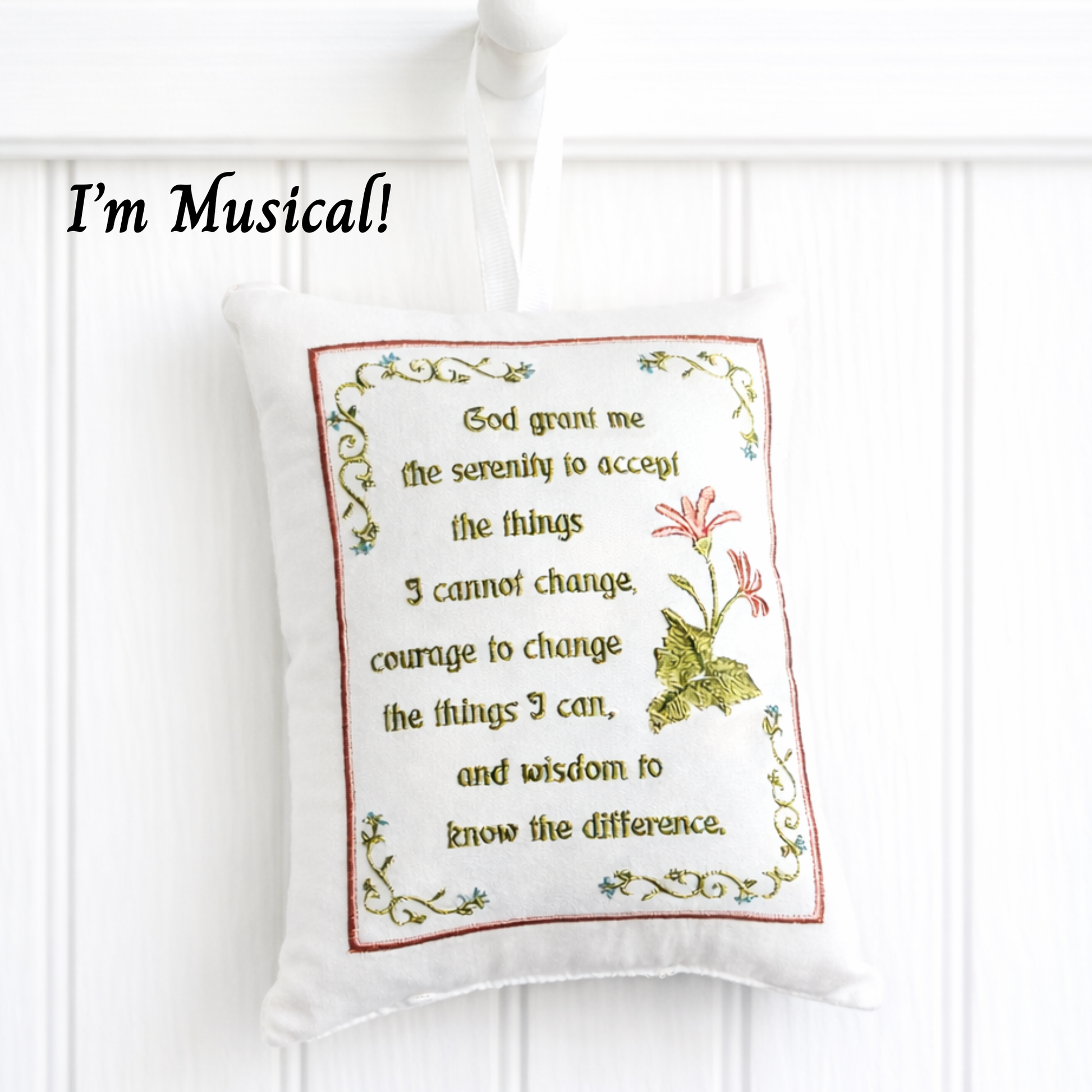 Decorative music box pillow with embroidered text and design on a white background