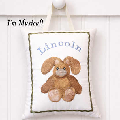 Decorative music box pillow with a bunny design and embroidered name 'Lincoln' on a white background.