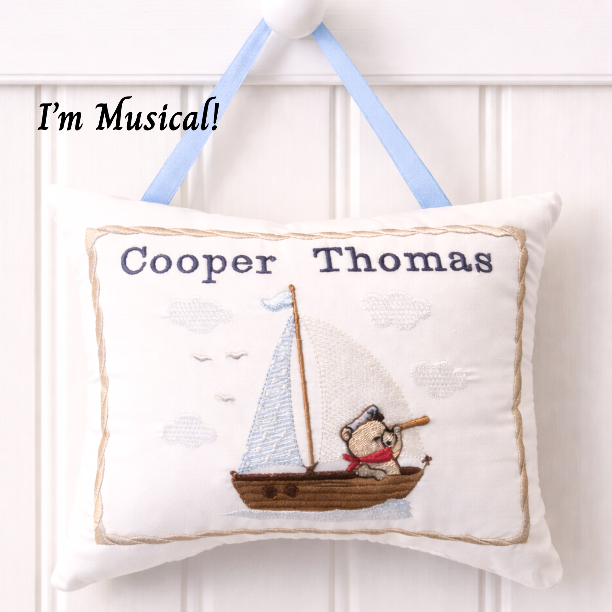 Decorative music box pillow with a teddy bear in a boat design and text 'Cooper Thomas' on a white background.