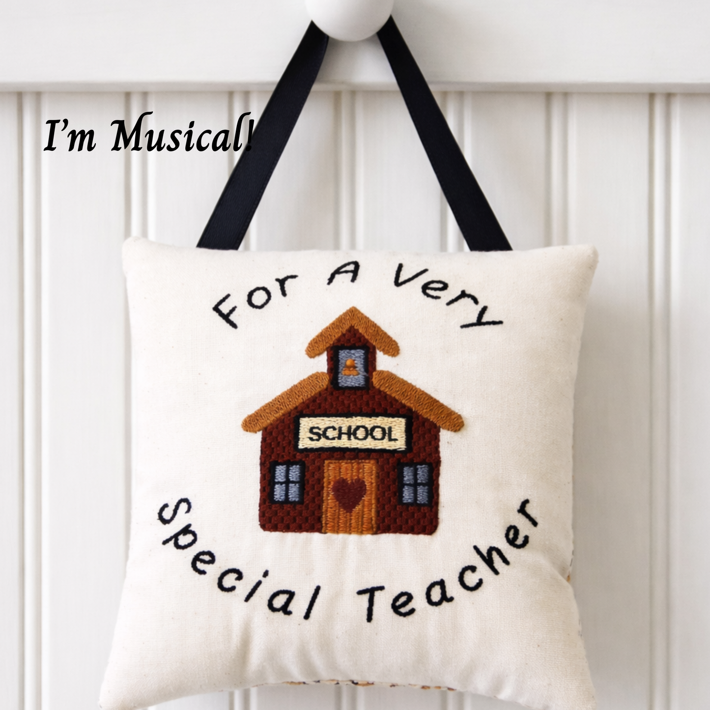 Decorative music box pillow with a schoolhouse design and text on a white background