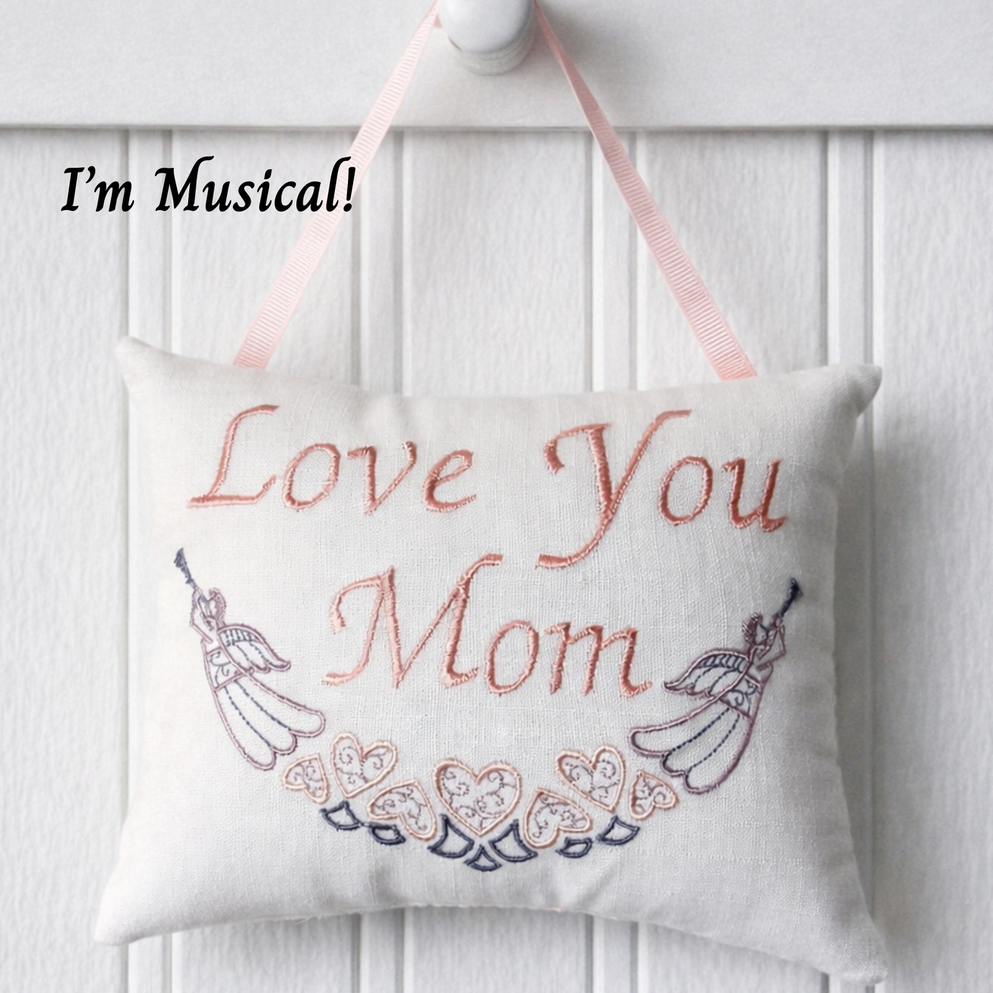 Decorative music box pillow with 'Love You Mom' text and musical notes on a white background