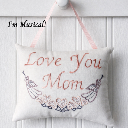 Decorative music box pillow with 'Love You Mom' text and musical notes on a white background