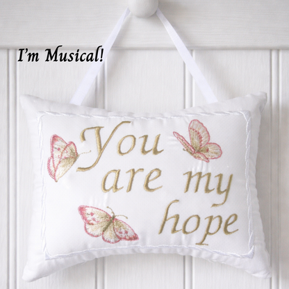 Decorative music box  pillow with embroidered text and butterflies on a white background