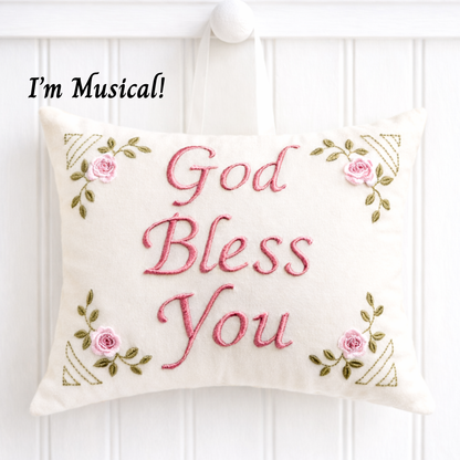 Decorative music box pillow with 'God Bless You' text and floral designs on a white background