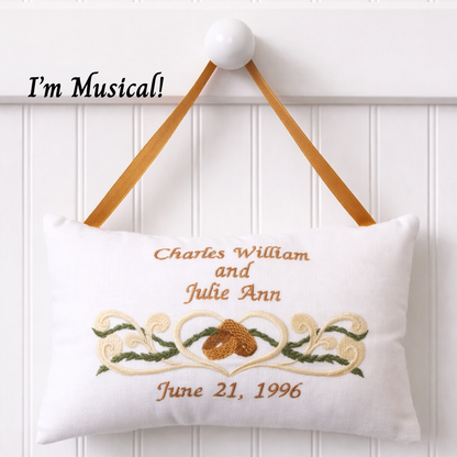 Decorative music box pillow with embroidered design and text on a white background
