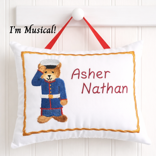 Decorative music box pillow with a teddy bear design and embroidered names on a white background