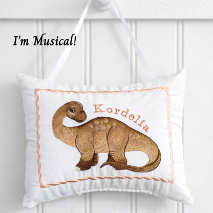Decorative music box pillow with dinosaur design and text 'I'm Musical!' on a white background