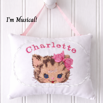 Decorative music box pillow with a cat face design and the name 'Charlette' on a white background.