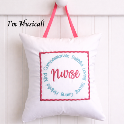 White music box pillow with embroidered text and pink straps on a white background