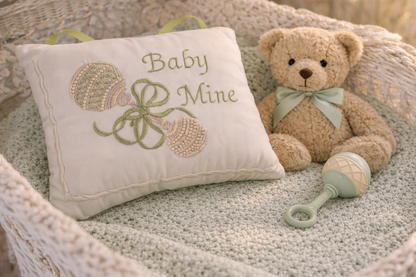 Baby music box pillow with 'Baby Mine' embroidery and teddy bear in a crib